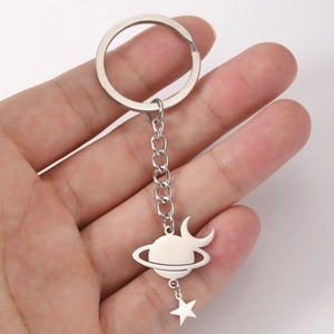 Polished stainless steel planet and star charm keychain held in hand for daily gift