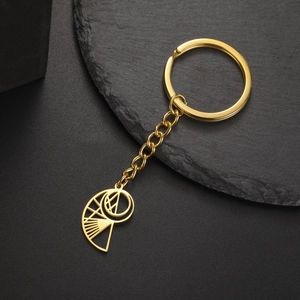 Macro detail of golden geometric cut-out conch pendant on a stainless steel keychain