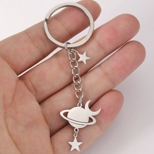 Detailed view of stainless steel keychain with star, moon, and planet charms in hand