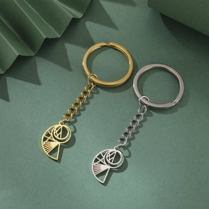 Close-up of geometric hollow conch pendants in gold and silver on textured green background