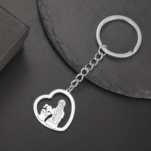 Détail d'un pendentif cœur argenté avec silhouette mère-enfant sur surface en pierre
