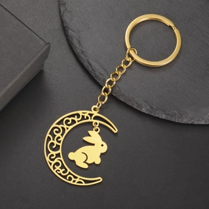 Détail d'un porte-clés lune doré avec motifs évidés et un petit pendentif lapin