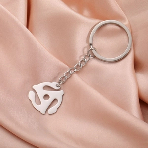 Detail of silver 45 RPM adapter keychain on elegant pink silk background