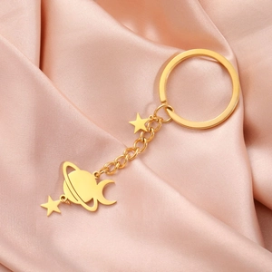 Detailed view of golden planet, star, and crescent moon charms on a metal keychain