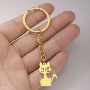 Detail of hand holding a golden stainless steel keychain with a minimalist cat pendant