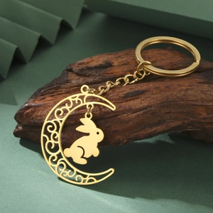 Gros plan du porte-clés lune évidée dorée avec pendentif lapin sur bloc de bois