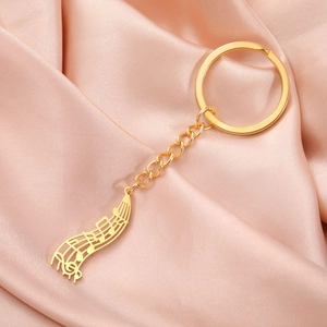 Détail du porte-clés pendentif musical en acier doré sur fond de soie rose satiné