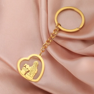 Détail d'un porte-clés cœur doré avec silhouette mère-fille sur du satin rose