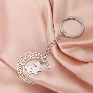 Détail du pendentif lune argenté avec motif ajouré et breloque lapin sur satin