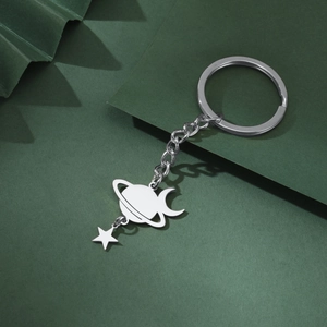Close-up of silver planet and star charms on keychain against a green background