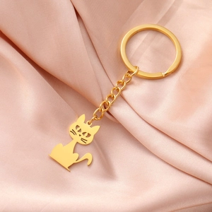 Detailed close-up of golden kitten pendant keychain on pink silk background