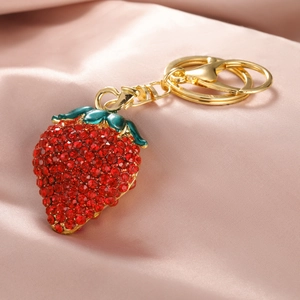 Porte-clés fraise étincelant en strass rouges et alliage doré sur fond de soie rose