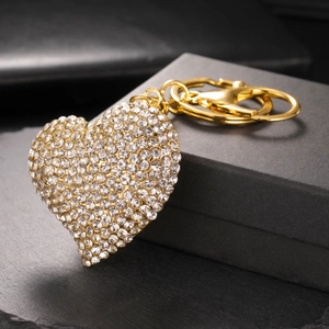 Sparkling gold heart keychain with clear crystals on dark slate background