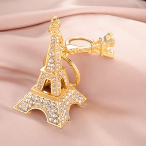 Golden Eiffel Tower keychain with crystals and crown charm on pink satin fabric