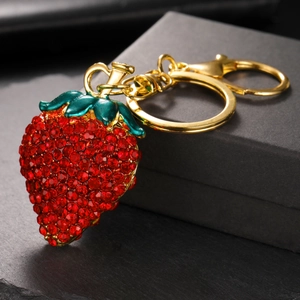 Porte-clés fraise serti de strass rouges avec fermoir mousqueton doré sur fond noir