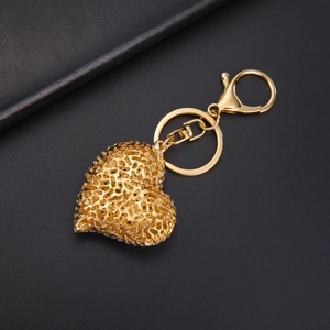 Exquisite hollow heart-shaped keychain in golden alloy with lobster clasp on leather background