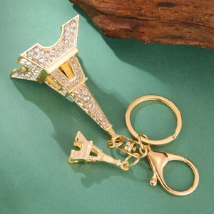 Golden Eiffel Tower keychain set with sparkling white rhinestones on green background