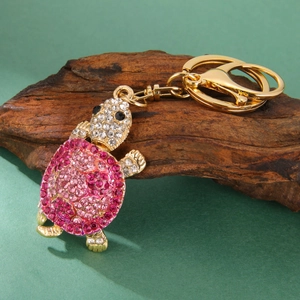 Pink rhinestone sea turtle keychain with gold alloy lobster clasp on wooden stand