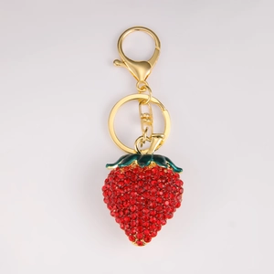 Détail d'un porte-clés fraise serti de strass rouges avec feuilles en émail et fermoir doré