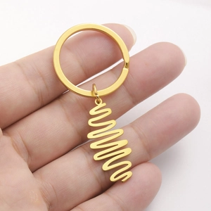 Fashionable gold stainless steel wave pendant keychain held in hand on white background