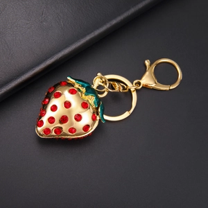 Détail d'un porte-clés fraise luxueux avec strass rouges et base en métal doré