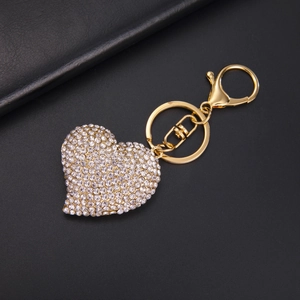 Macro view of gold heart keychain with white crystals on black leather background