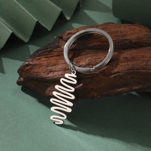 Polished stainless steel spiral pendant keychain on dark wood block background