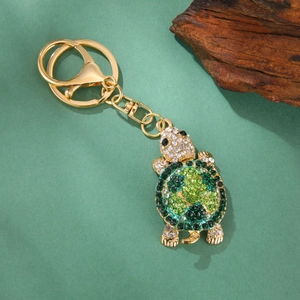 Close-up of golden turtle keychain with gradient green crystals and lobster clasp