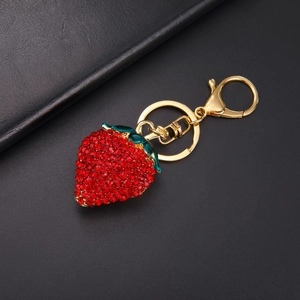 Détail du porte-clés fraise orné de strass rouges et de finitions en émail vert élégant