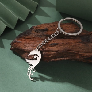 Polished stainless steel phoenix keychain pendant with link chain on a rustic wood base