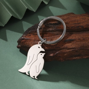Minimalist penguin duo stainless steel keychain on a natural bark textured surface