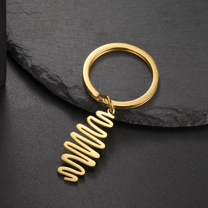 Detailed view of glossy gold spiral pendant and keyring on a dark textured background
