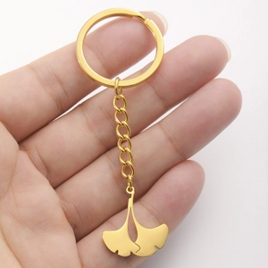 Polished gold ginkgo leaf keychain in stainless steel held in hand for scale