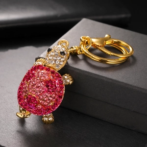 Detail of crystal turtle keychain with pink and red rhinestones on black gift box