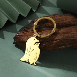Macro detail of golden mirror stainless steel penguin charms on rustic wood background