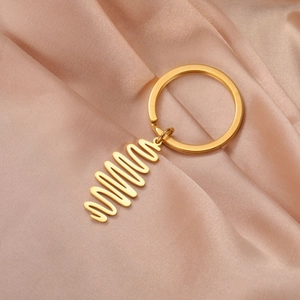 Macro detail of a wavy gold titanium keychain pendant on champagne silk fabric background