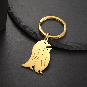 Detail of golden stainless steel penguin silhouette charms on a black slate surface