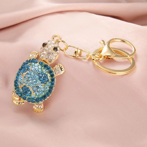 Macro shot of sea turtle keychain with blue crystal gradient on pink silk background