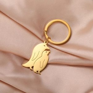 Close-up of golden penguin pendant keychain on champagne silk background texture