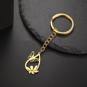 Detail view of a golden stainless steel keychain with hollow butterfly and floral teardrop pendant