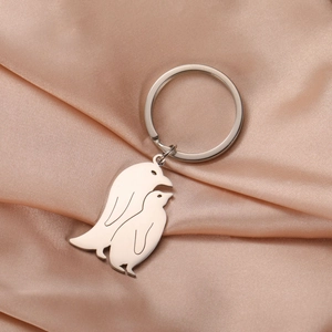 Detailed view of polished stainless steel penguin pendants on a champagne silk fabric background