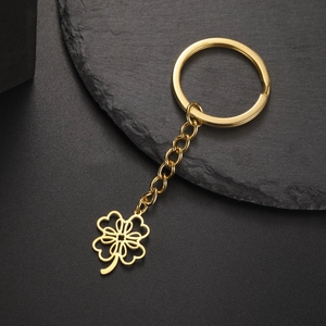 Detail of a polished gold hollow four-leaf clover keychain on a black stone base