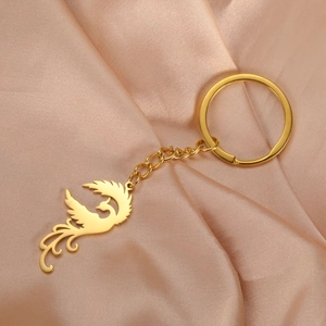 Detailed view of a golden phoenix pendant keychain on elegant champagne satin fabric