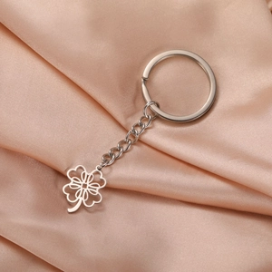 Detail shot of hollow four-leaf clover keychain on champagne satin fabric background