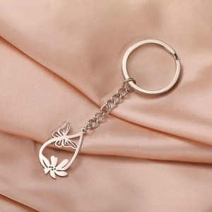 Detailed macro view of a silver hollow butterfly pendant on a polished steel keychain