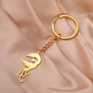 Macro shot of gold phoenix pendant keychain with chain on champagne satin background