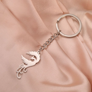 Detailed close-up of a Phoenix cutout pendant keychain on soft pink silk fabric