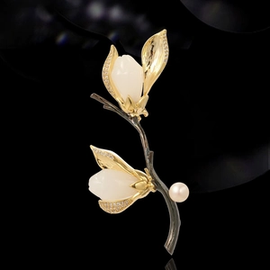 Élégante broche magnolia avec pétales en jade, finition dorée et perle sur fond noir