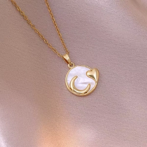 Collier vintage doré avec nacre blanche, pendentif lune et cœur sur du satin