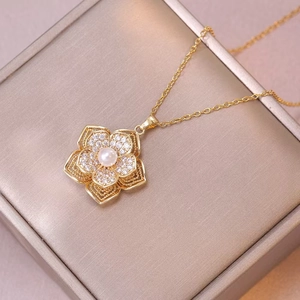Goldene Blumenkette mit Zirkonia-Blütenblättern und zentraler Perle auf Geschenkbox